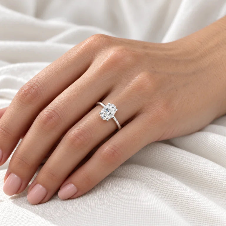 Bare-wrist close-up of a model wearing an oval diamond solitaire engagement ring