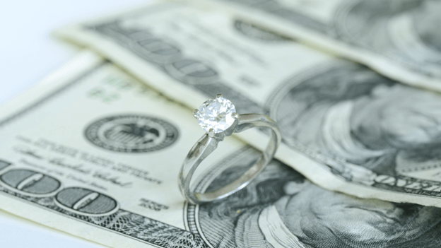 an engagement ring sits on money