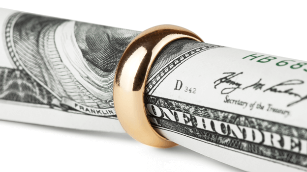 a one-hundred dollar bill wrapped in a gold wedding ring