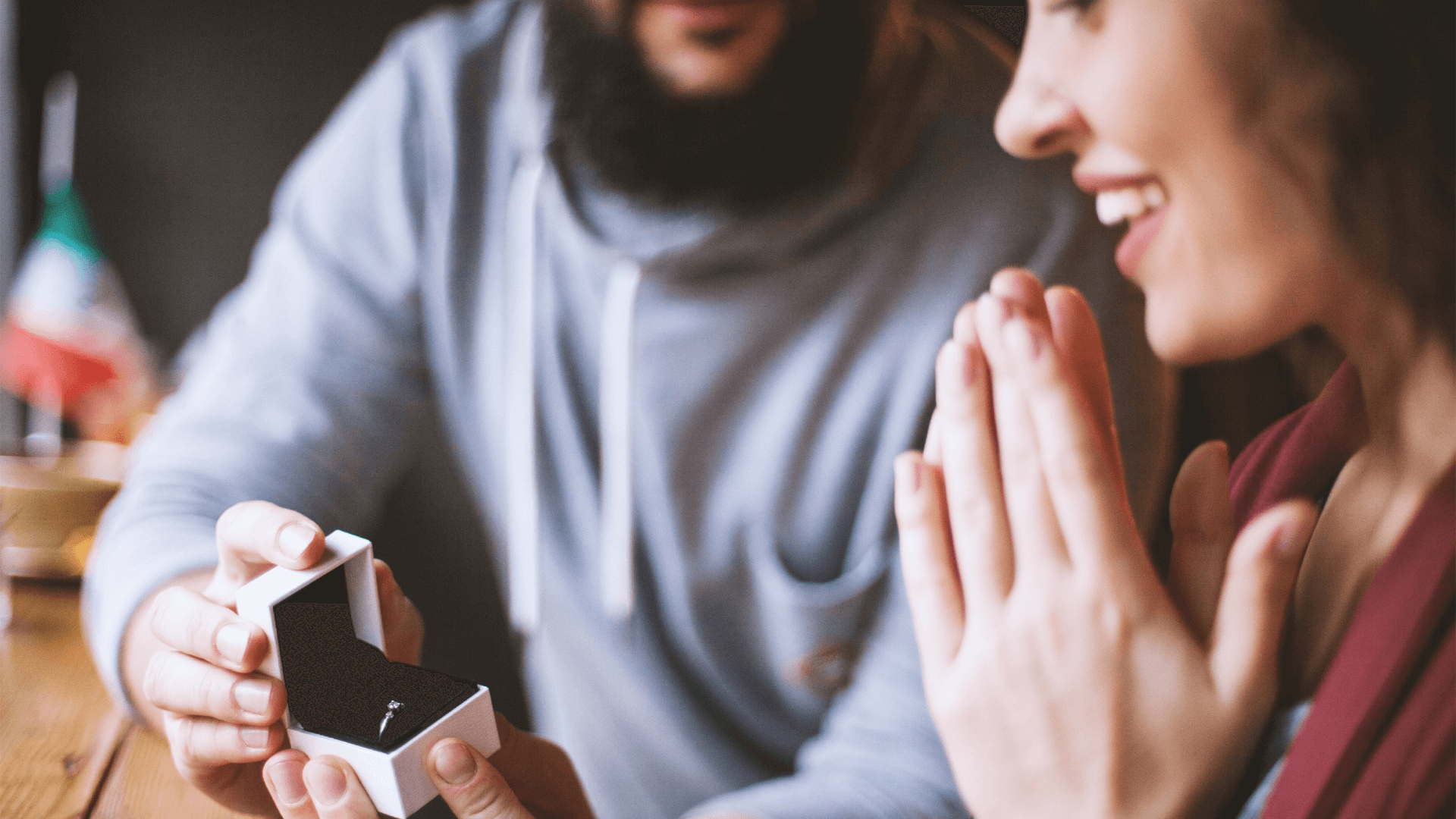 a man proposes to a woman with a boxed diamond engagement ring