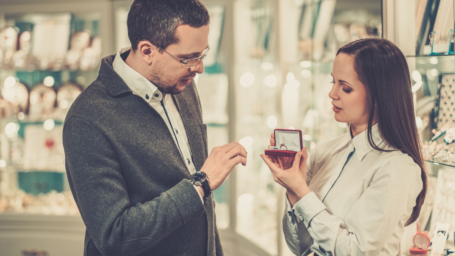 a man shops for an engagement ring with help from an assistant