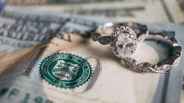 wedding bands sit on top of dollar bills