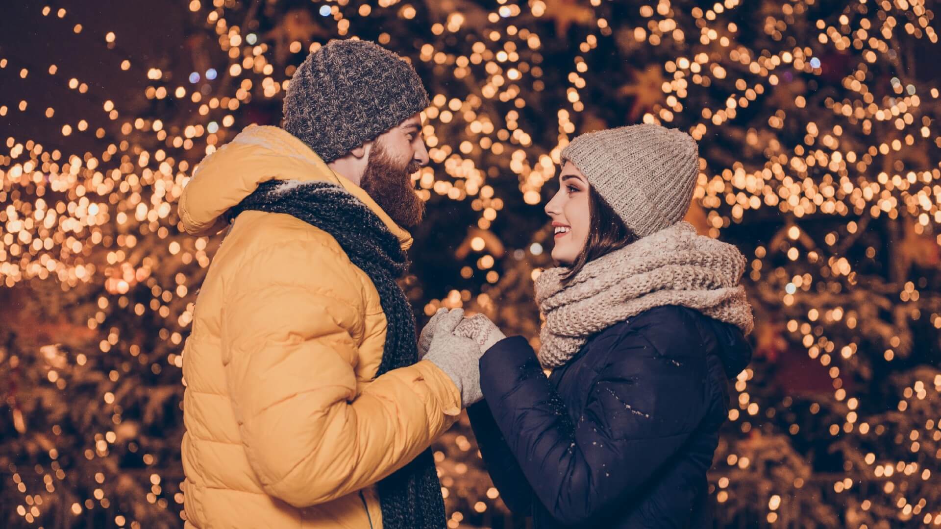 a couple has a marriage proposal in front of Christmas lights
