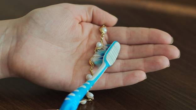 a person is cleaning a pearl necklace with a brush