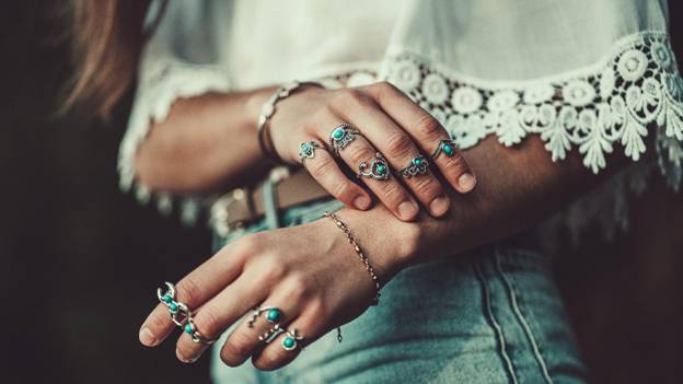 a woman is wearing rings and a crochet top