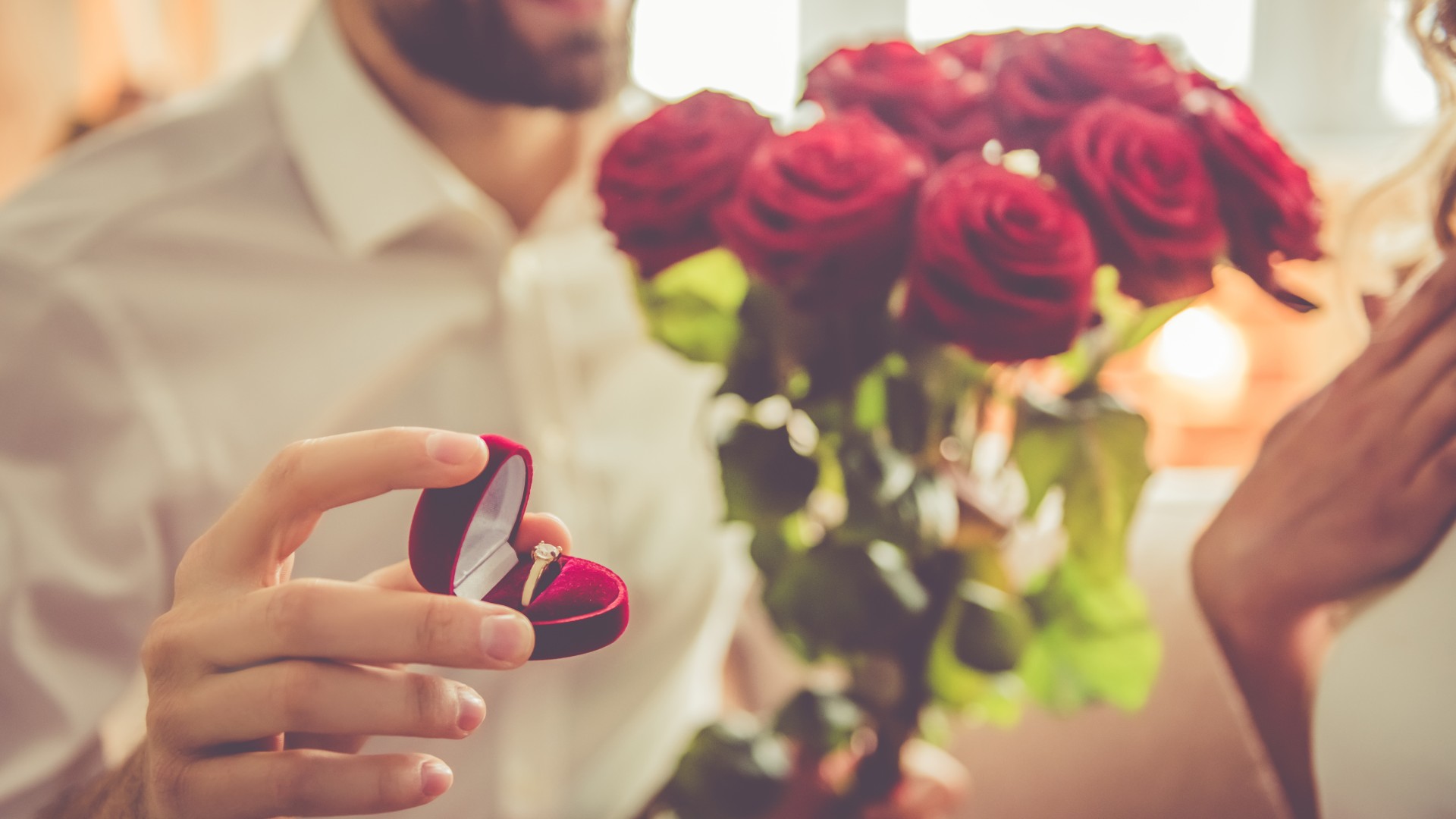 9 Perfect Engagement Rings for Your Forever Valentine: a person proposes with an engagement ring and a bouquet of roses