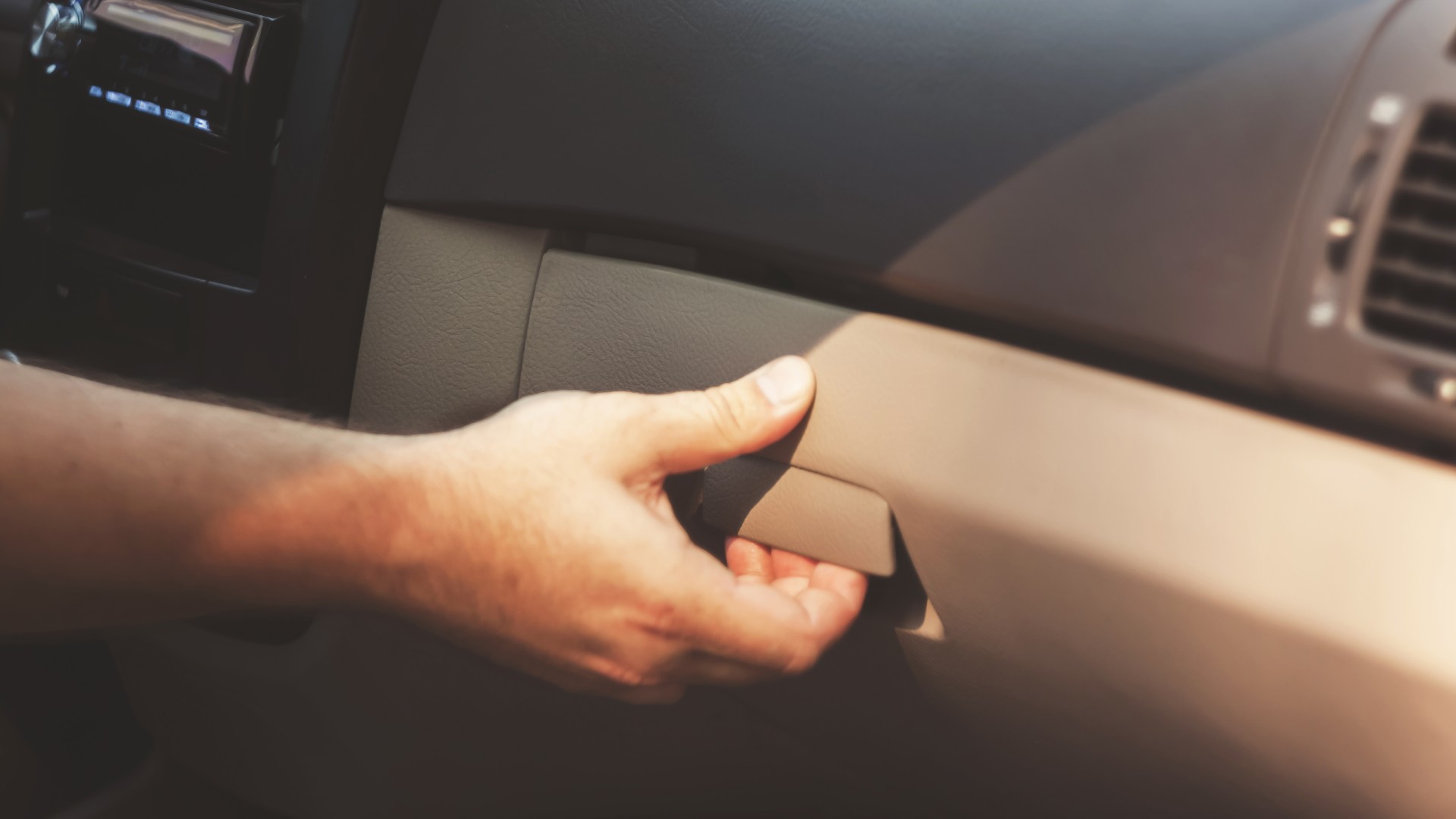 a person opens a car glove compartment to look for jewelry