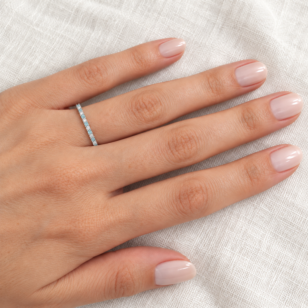 Petite aquamarine and diamond white-gold eternity band on left ring finger, ivory linen closeup