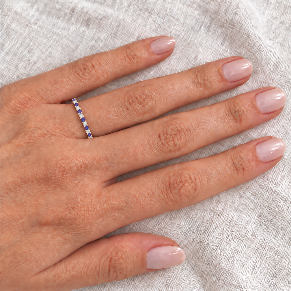14k rose gold tanzanite and diamond eternity band on left ring finger, closeup on ivory linen