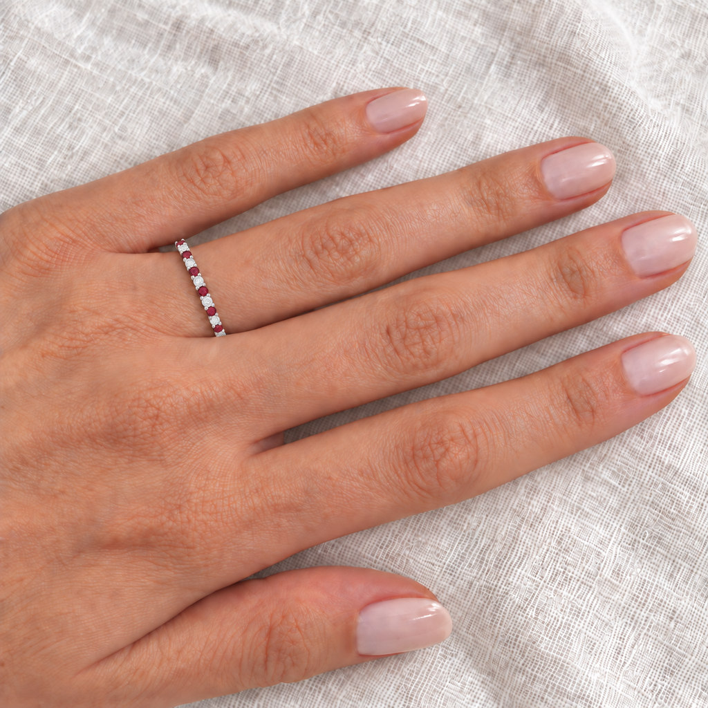 Ruby and diamond white gold eternity band on left ring finger, closeup on ivory linen