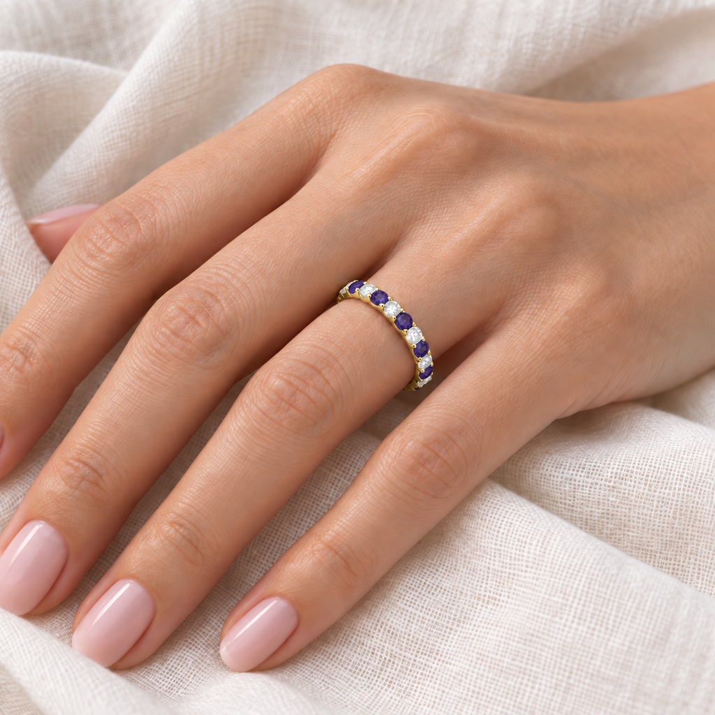 AZ10716 lab alexandrite and diamond eternity band in 14k yellow gold, close-up on left hand over ivory linen