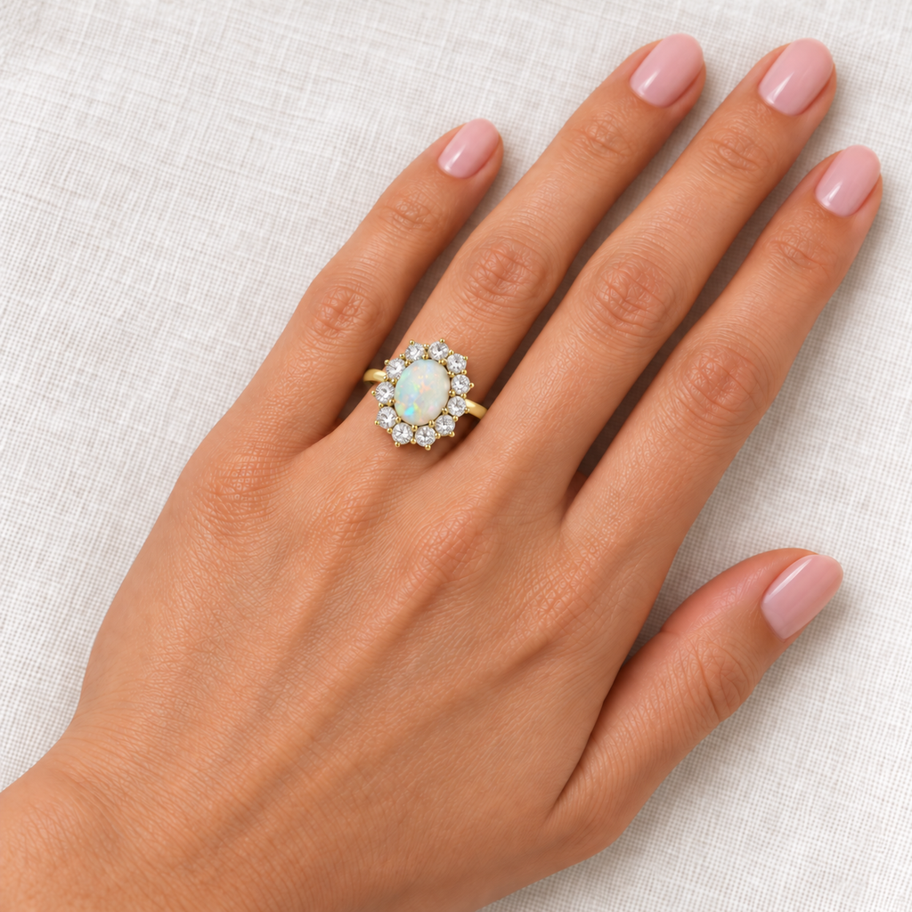 Natural 9 x 7 mm smooth Australian opal and twelve-diamond Lady Diana halo ring in 14k yellow gold, aligned lengthwise at base of left ring finger over ivory linen