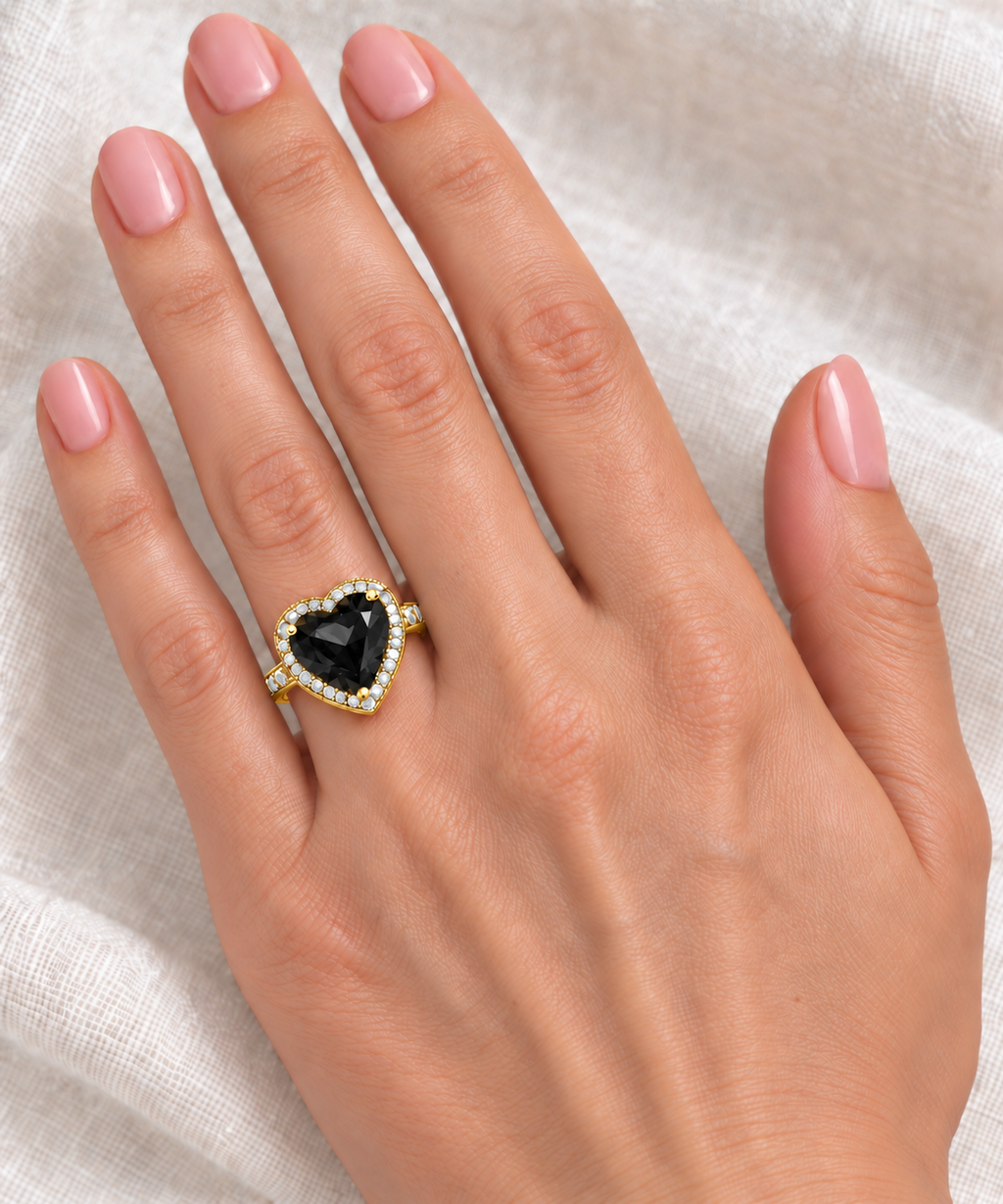 12x12mm heart-shaped lab black diamond and white diamond halo ring in 14k yellow gold, 5.41ct — correctly scaled at base of left ring finger on ivory linen