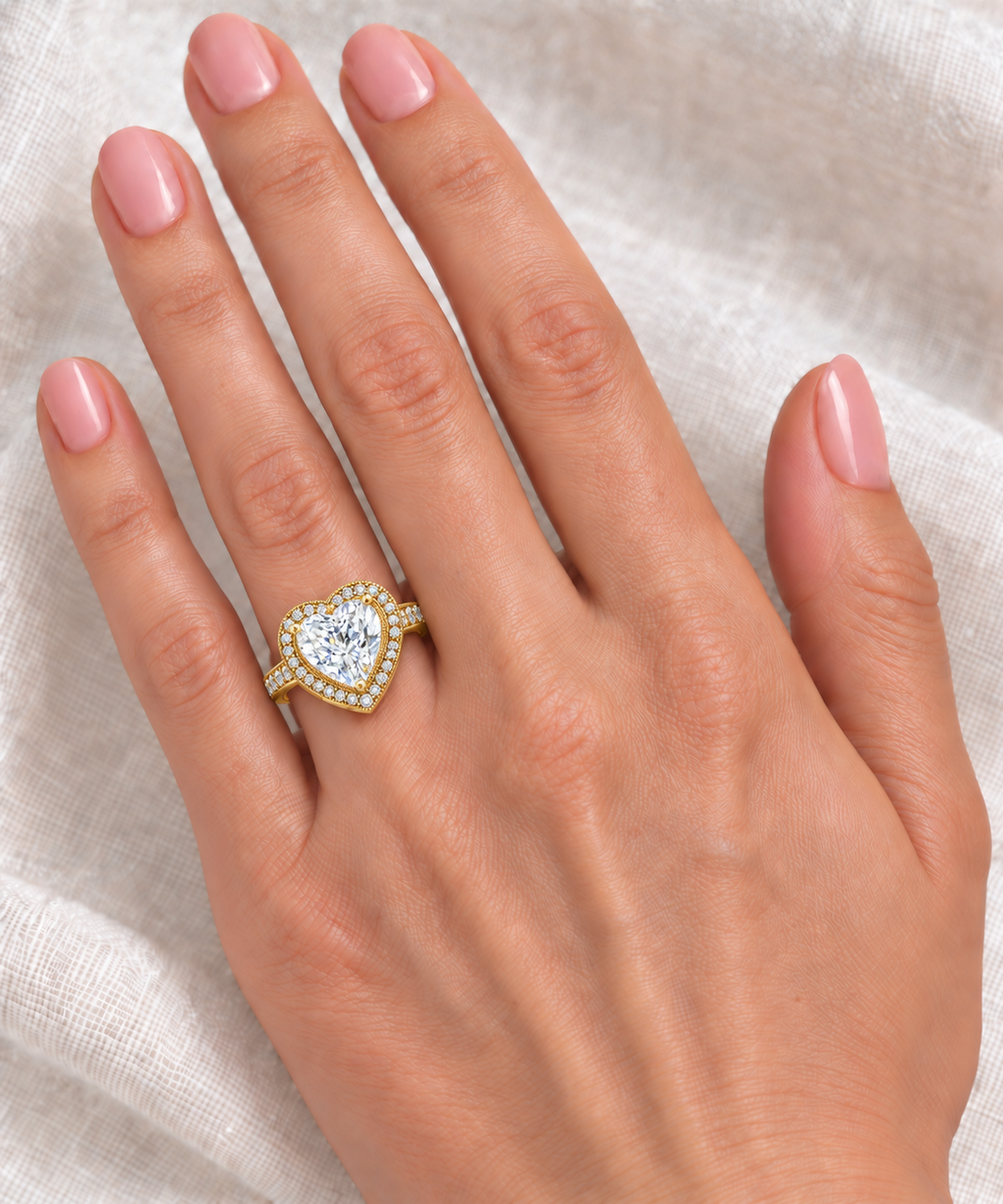 10x10mm heart-shaped lab diamond and white diamond halo ring in 14k yellow gold, 3.66ct — correctly scaled at base of left ring finger on ivory linen