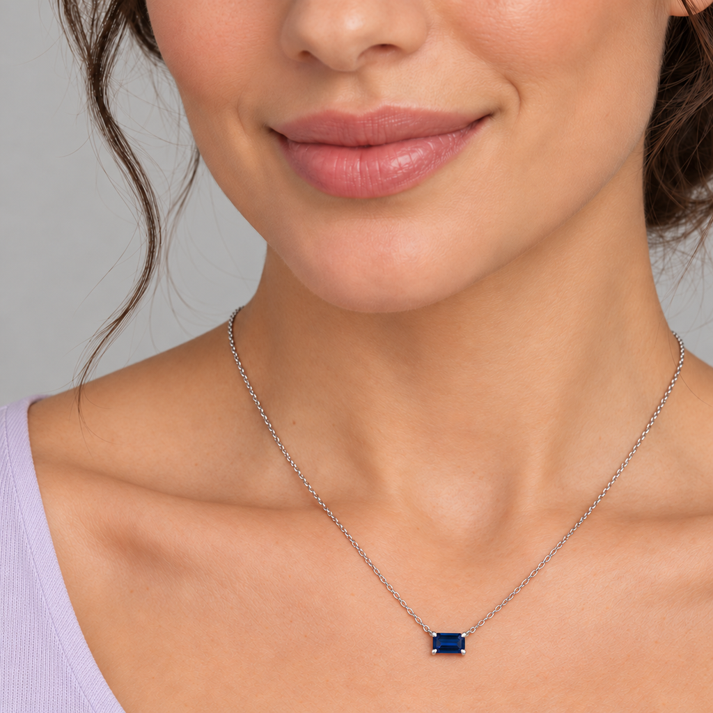 AZ29488 — close-up model wearing 5 × 3 mm emerald-cut lab-grown blue sapphire solitaire necklace in sterling silver on an 18-inch cable chain; illustrative scale.