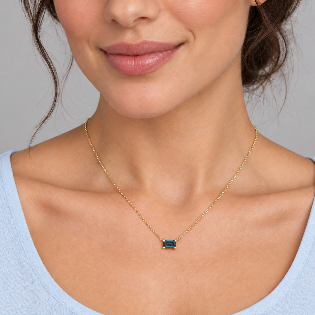 AZ29490 — close-up model wearing 5 × 3 mm emerald-cut lab-grown alexandrite solitaire necklace in 14K yellow gold on an 18-inch cable chain; illustrative scale.