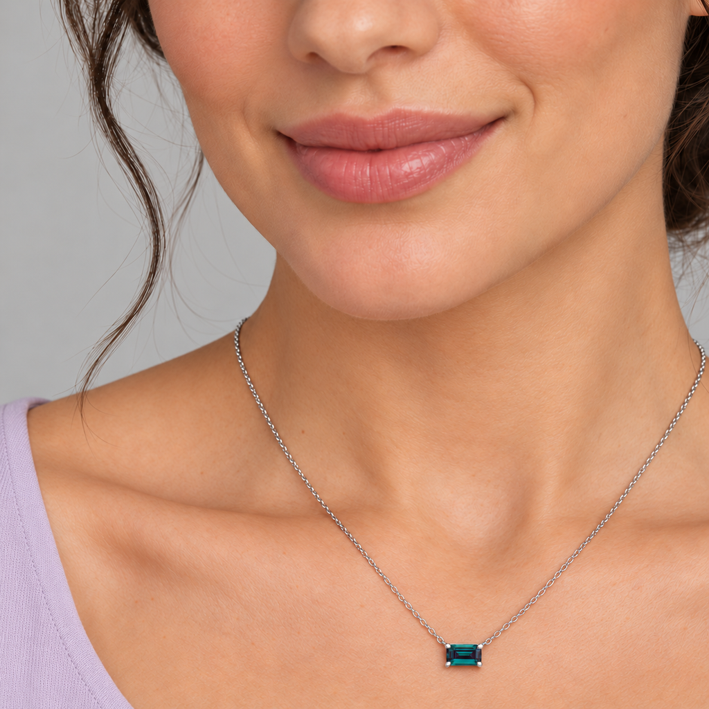 AZ29491 — close-up model wearing 5 × 3 mm emerald-cut lab-grown alexandrite solitaire necklace in sterling silver on an 18-inch cable chain; illustrative scale.