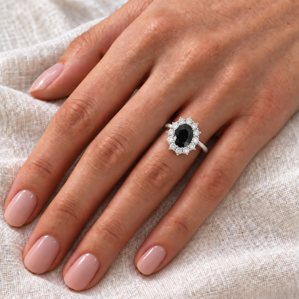 Oval natural black diamond and 12-diamond halo ring in 14k white gold on left hand over ivory linen