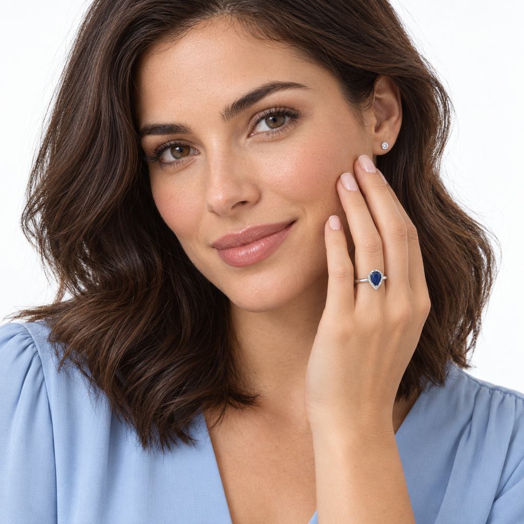 Natural pear blue sapphire and diamond halo ring in 14K white gold worn in professional studio portrait