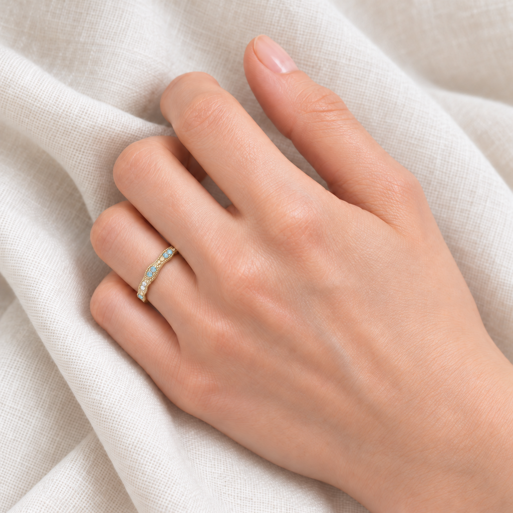 Vintage natural aquamarine and diamond stacking ring in 14k yellow gold on a left hand over ivory linen