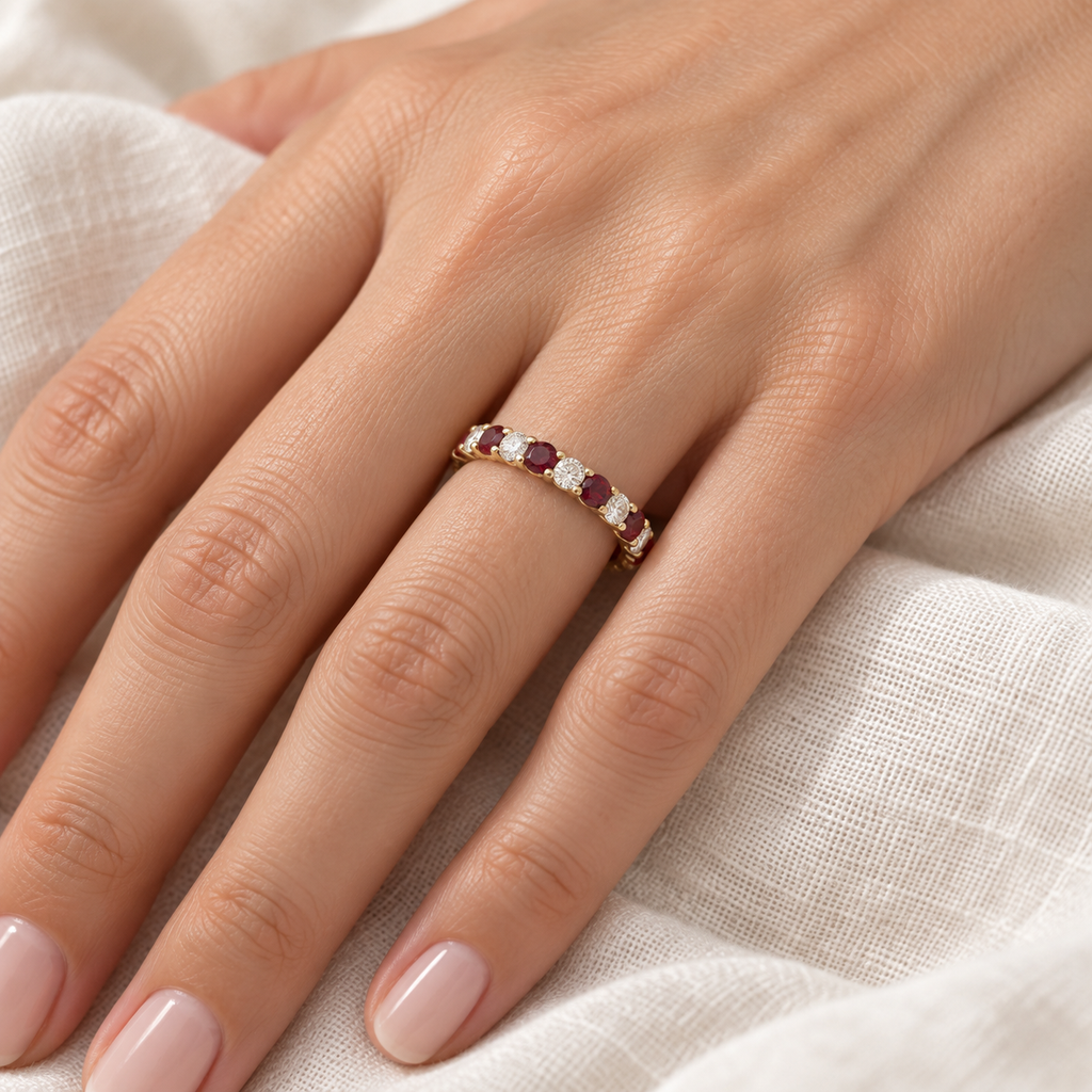 Eternity diamond and garnet ring band in 14k yellow gold worn on left hand on ivory linen