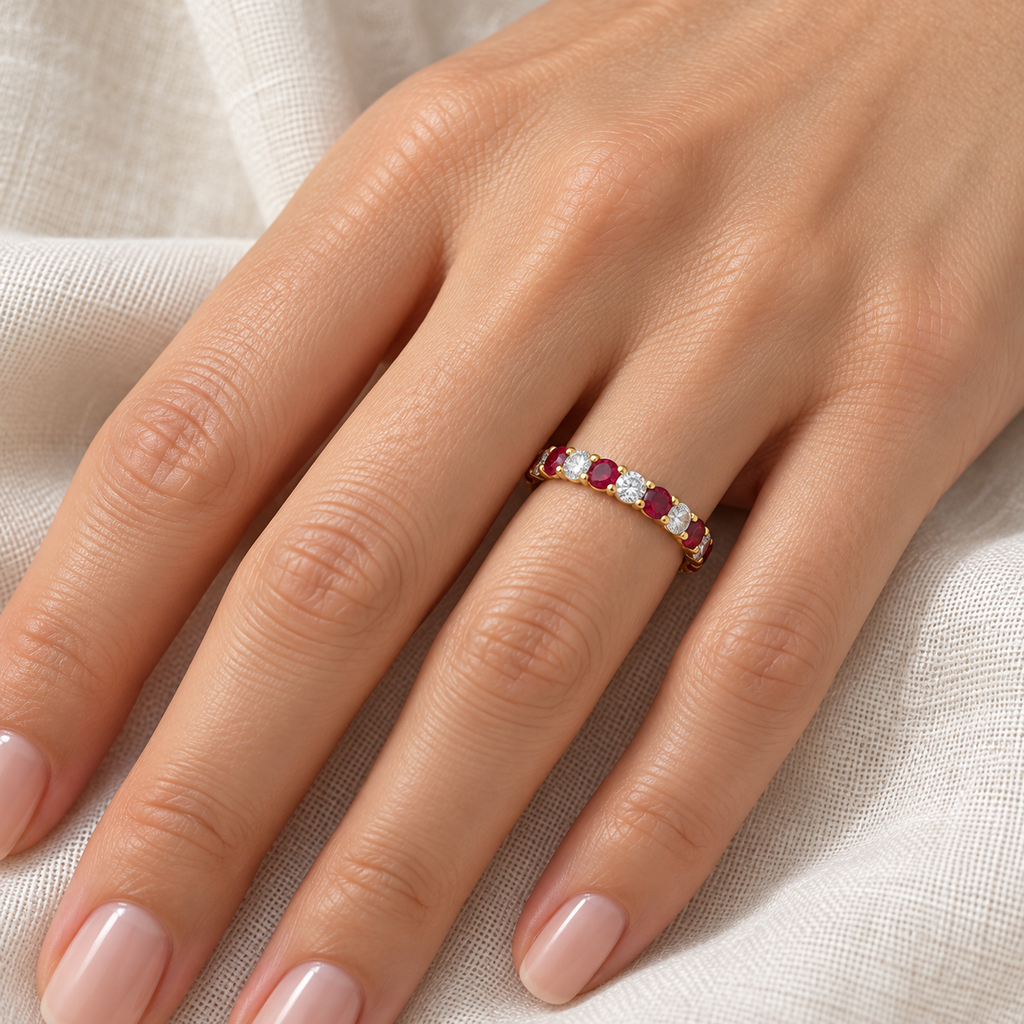 Lab-grown diamond and ruby eternity ring band in 14k yellow gold worn on left hand on ivory linen