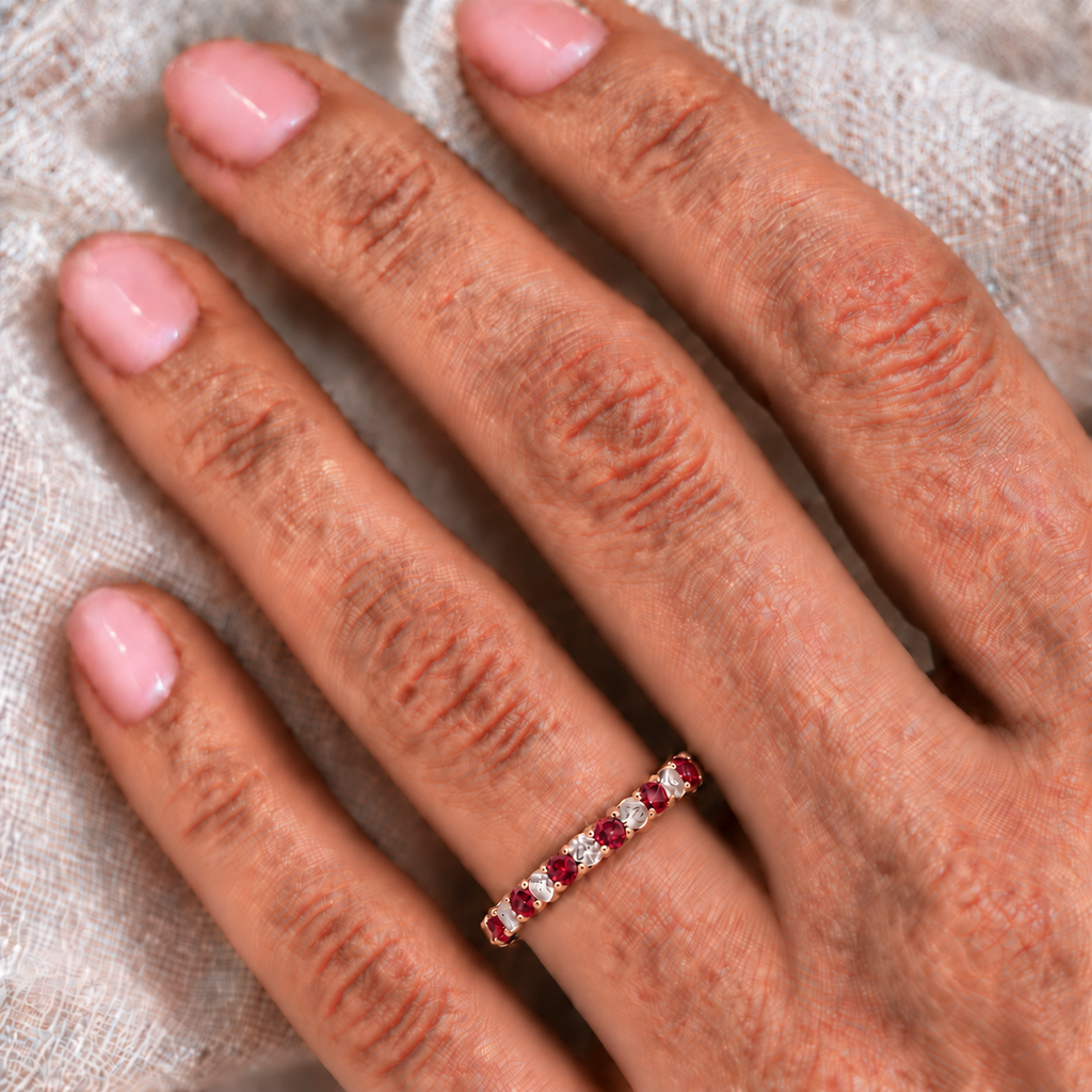 Lab-grown ruby and lab-grown diamond 3mm eternity ring band in 14k rose gold on the left ring finger against ivory linen