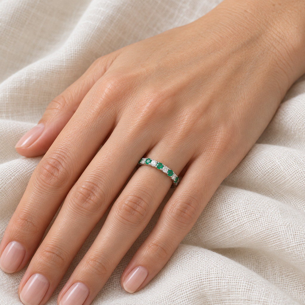 Lab-grown emerald and lab-grown diamond 14K white gold 2 mm eternity band on left hand, ivory linen closeup