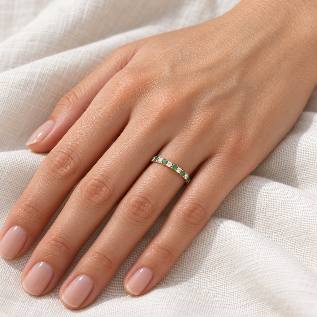 Lab-grown emerald and lab-grown diamond 14K rose gold 2 mm eternity band on left hand, ivory linen closeup