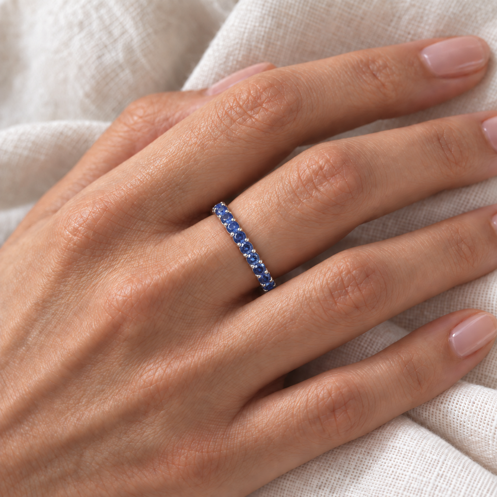 Lab Blue Sapphire Eternity Ring Anniversary Band 14k White Gold (1.07ct) — fine-scale close-up on left hand over ivory linen