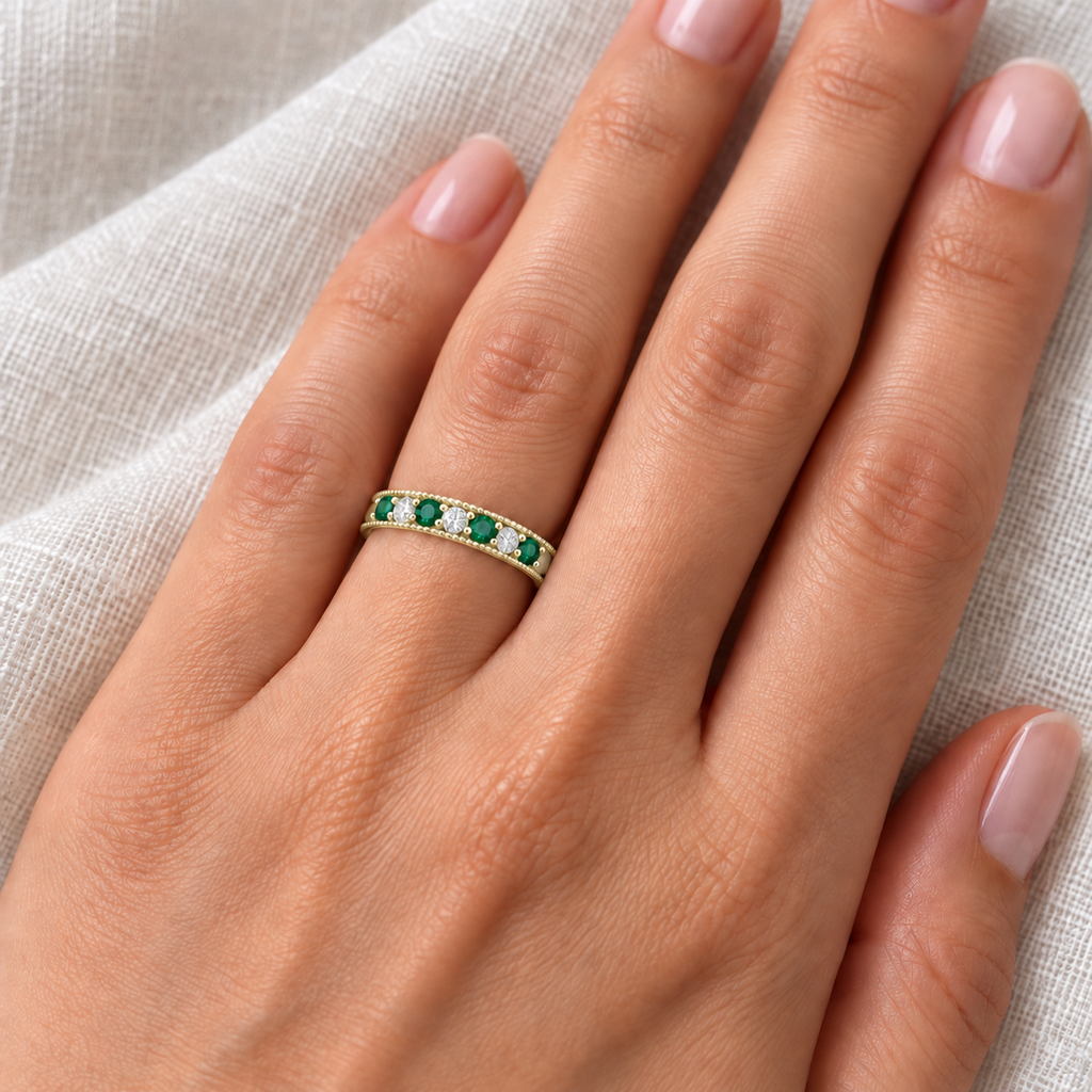 Emerald and diamond 3mm yellow gold band on left ring finger, ivory linen closeup
