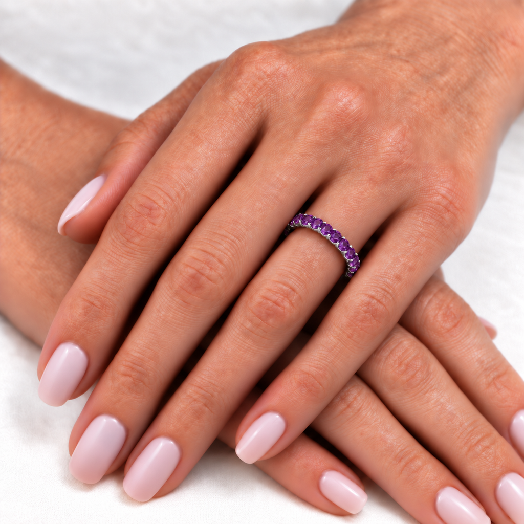Purple amethyst eternity ring band in 14k white gold on left hand, ivory linen closeup