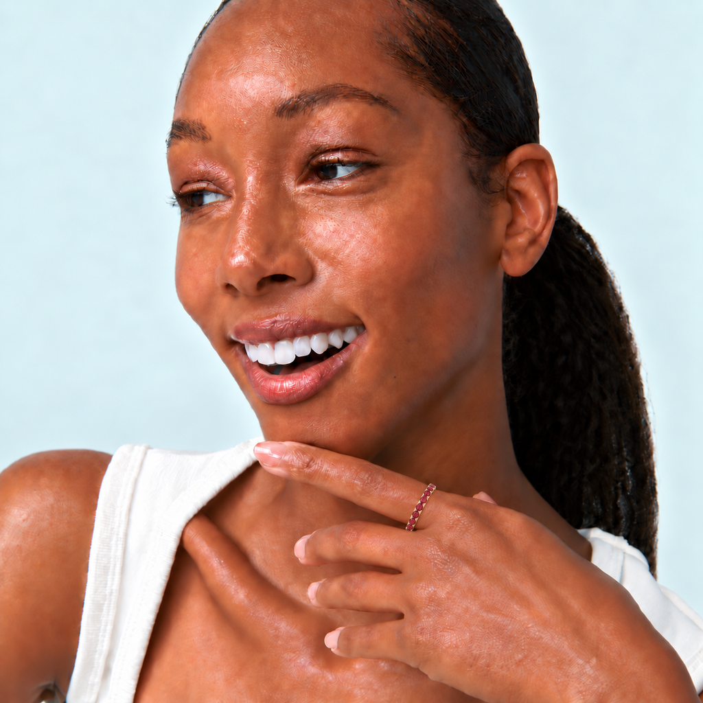 Model wearing a lab red garnet eternity ring in 14k yellow gold in a near-white studio portrait