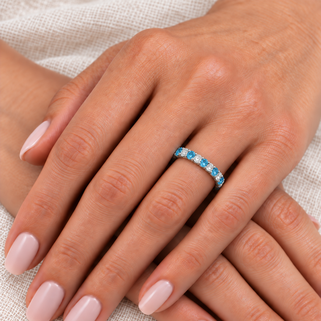 Natural blue topaz and diamond eternity band in 14k white gold, fine 3mm scale, on left ring finger over ivory linen