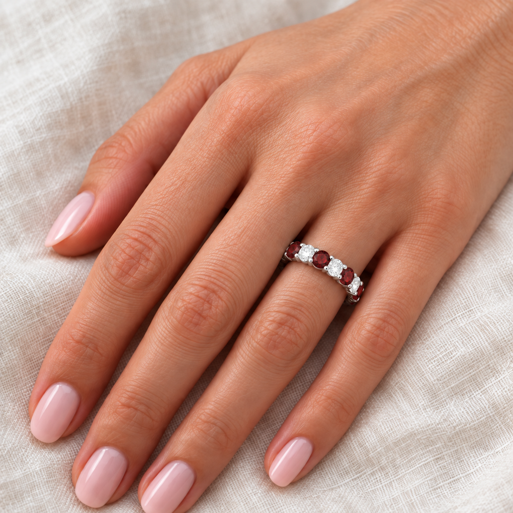 Eternity diamond and garnet anniversary ring band on left hand over ivory linen