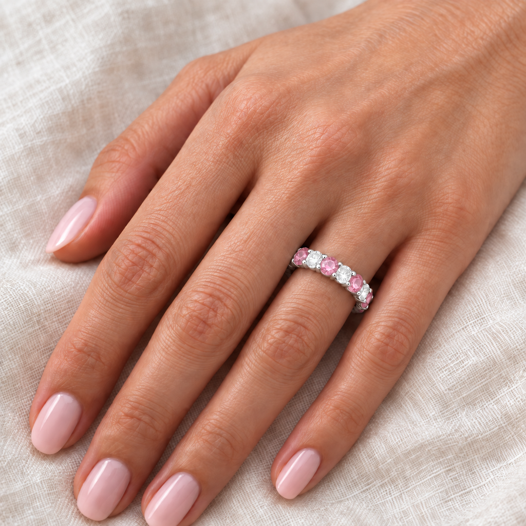 Eternity diamond and light pink sapphire ring band on left hand over ivory linen
