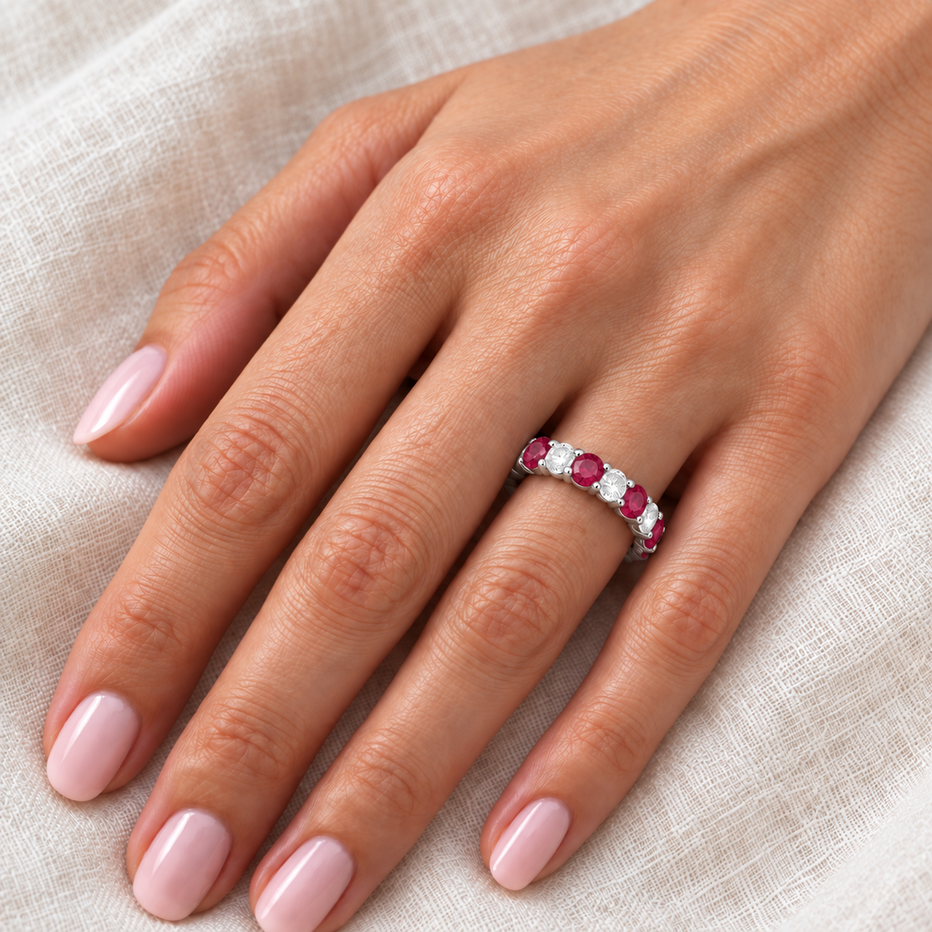 Eternity diamond and ruby anniversary ring band on left hand over ivory linen
