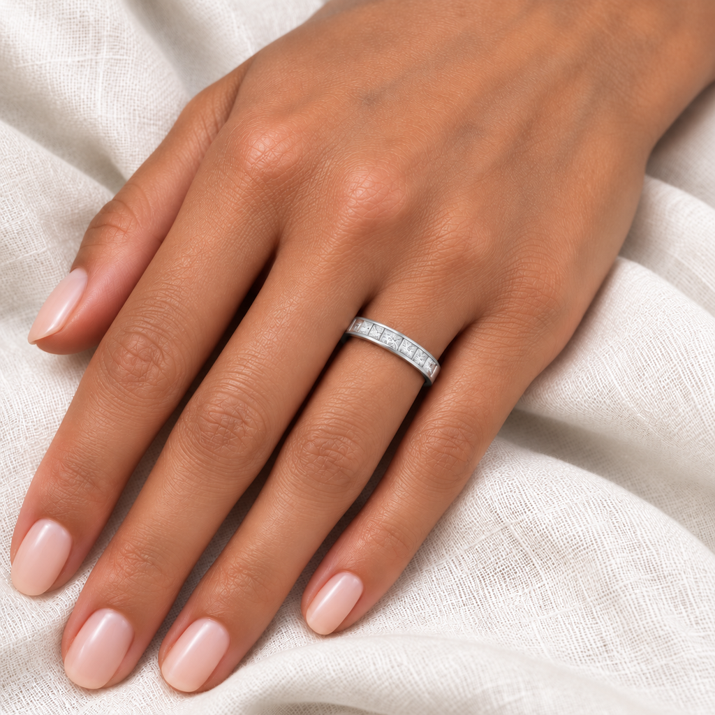 Nine lab-grown princess-cut diamonds in 14k white gold 4mm channel-set band, worn at base of left ring finger on ivory linen