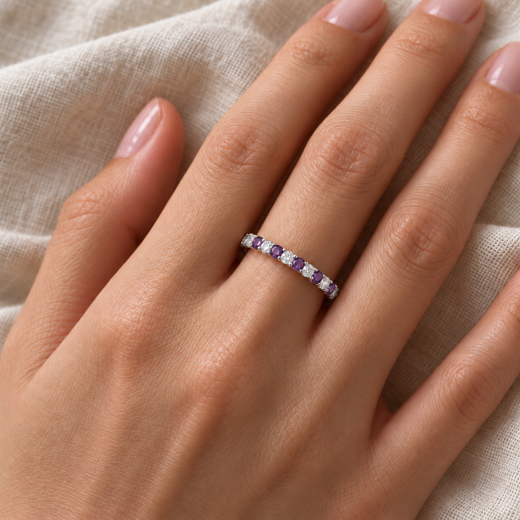 Amethyst and diamond wedding band in 14k white gold on left ring finger against ivory linen