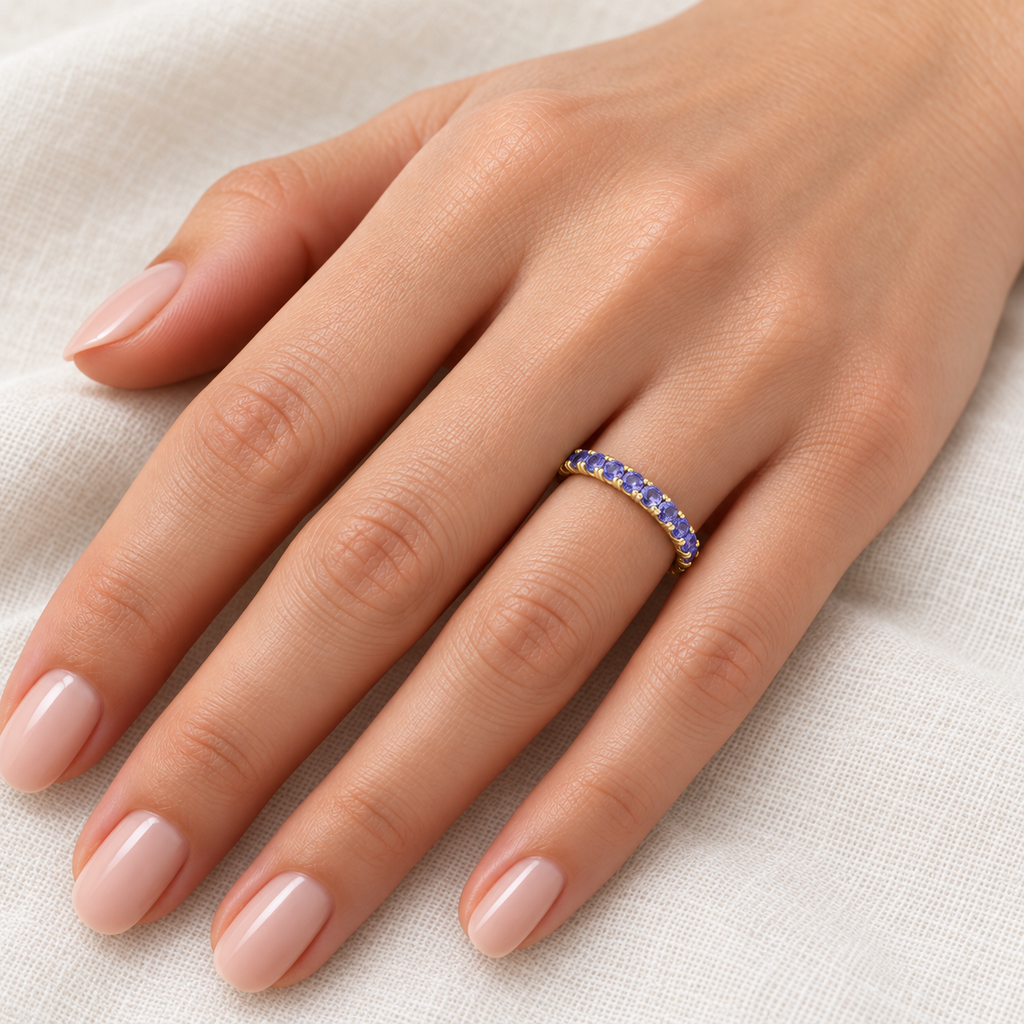 Tanzanite 14K yellow gold 2 mm eternity band on left hand, ivory linen closeup