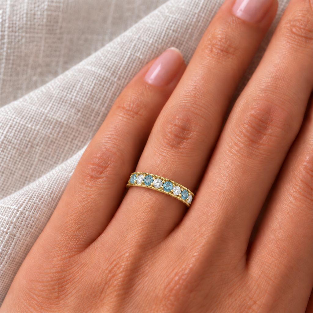 Aquamarine and diamond yellow gold ring on left hand, ivory linen closeup