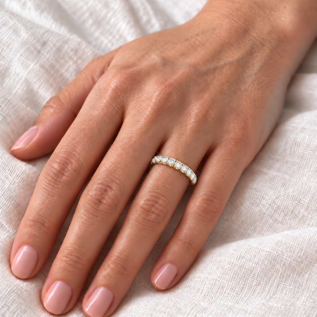 Lab-grown diamond semi-eternity band in polished 14k yellow gold, 2.5mm, fifteen round brilliant diamonds in four-prong settings — ivory-linen closeup on left ring finger