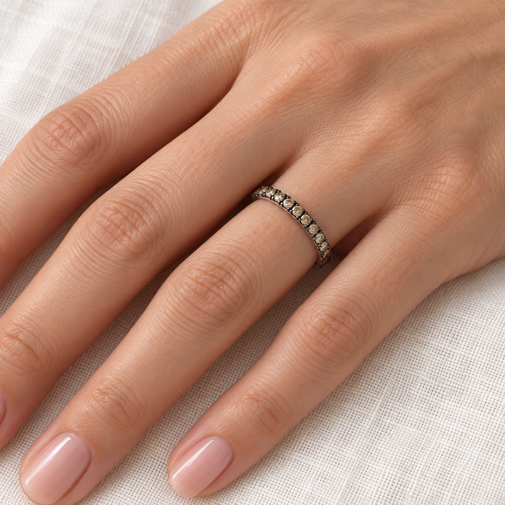 Champagne diamond 14K white gold eternity band on left hand, close-up on ivory linen