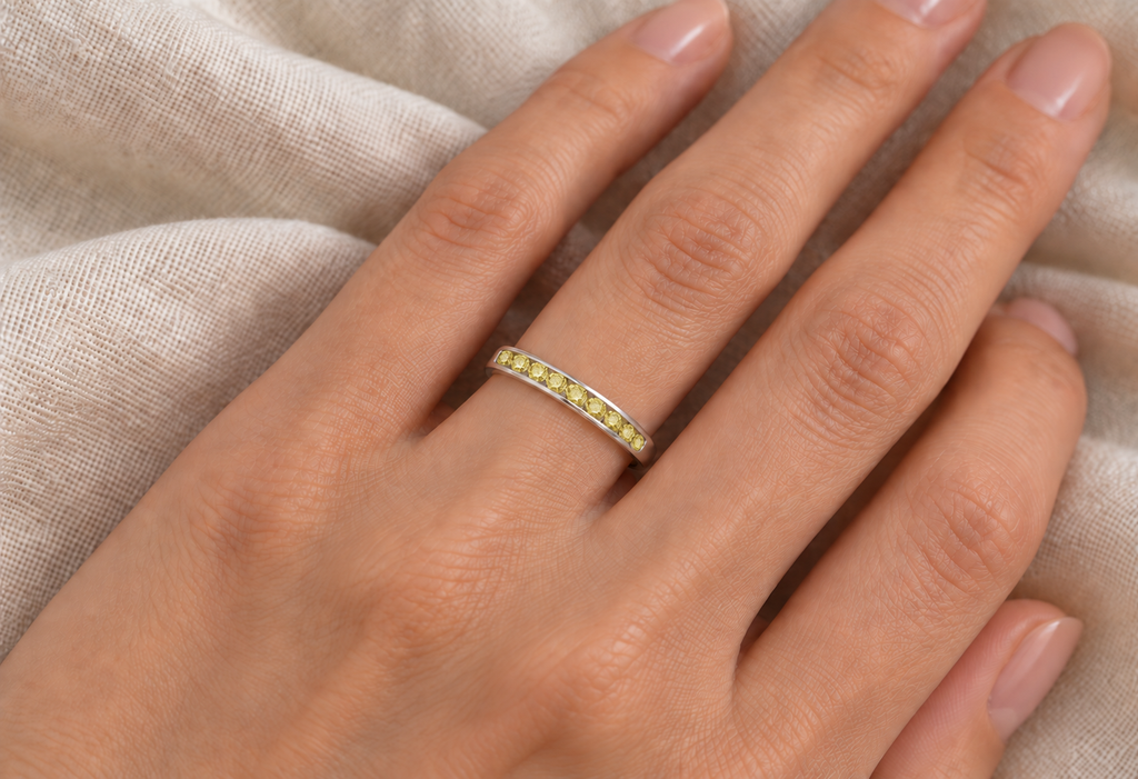 IR460 natural fancy-yellow canary diamond channel band on left ring finger, ivory linen close-up