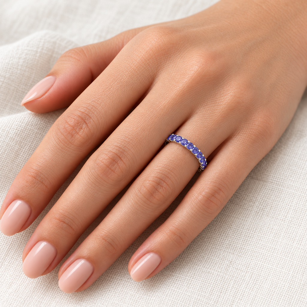 Tanzanite 14K white gold 2 mm eternity band on left hand, ivory linen closeup