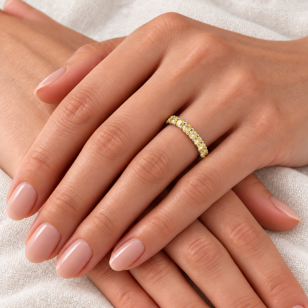 Fancy Yellow Canary Diamond Eternity Band 14k Yellow Gold (2.00ct) — close-up on left ring finger over light ivory linen