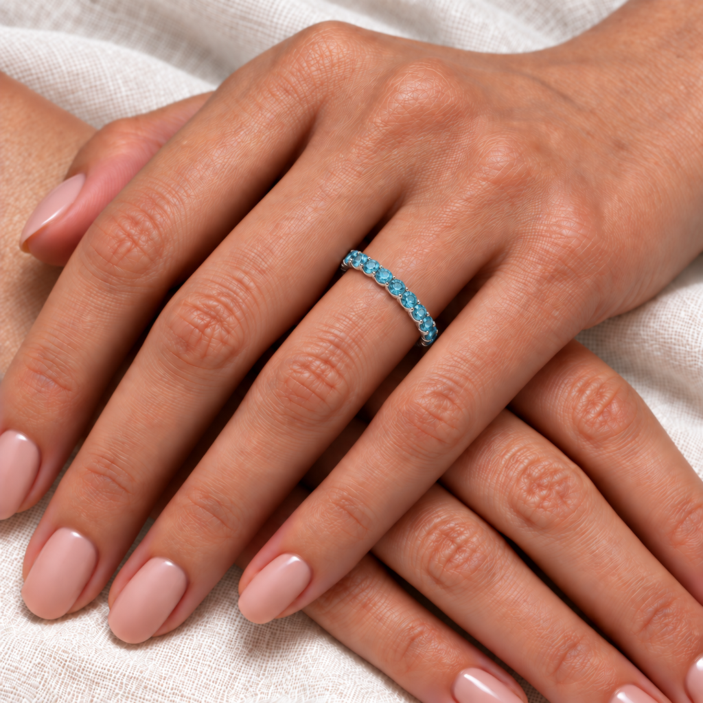 Fancy Blue Diamond Eternity Ring Band 14k White Gold (1.07ct) — close-up on left ring finger over light ivory linen