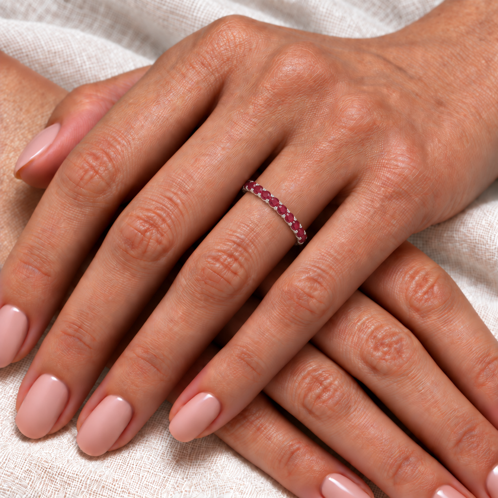 Natural ruby eternity ring in 14k white gold worn on hand, ivory linen close-up