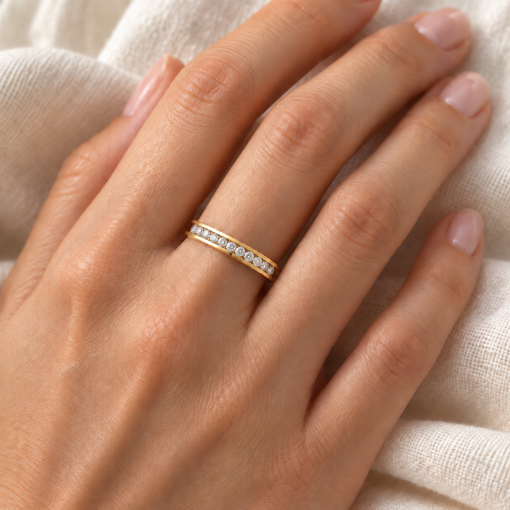 Fine 3 mm channel-set natural diamond band in yellow gold on left ring finger, ivory linen closeup