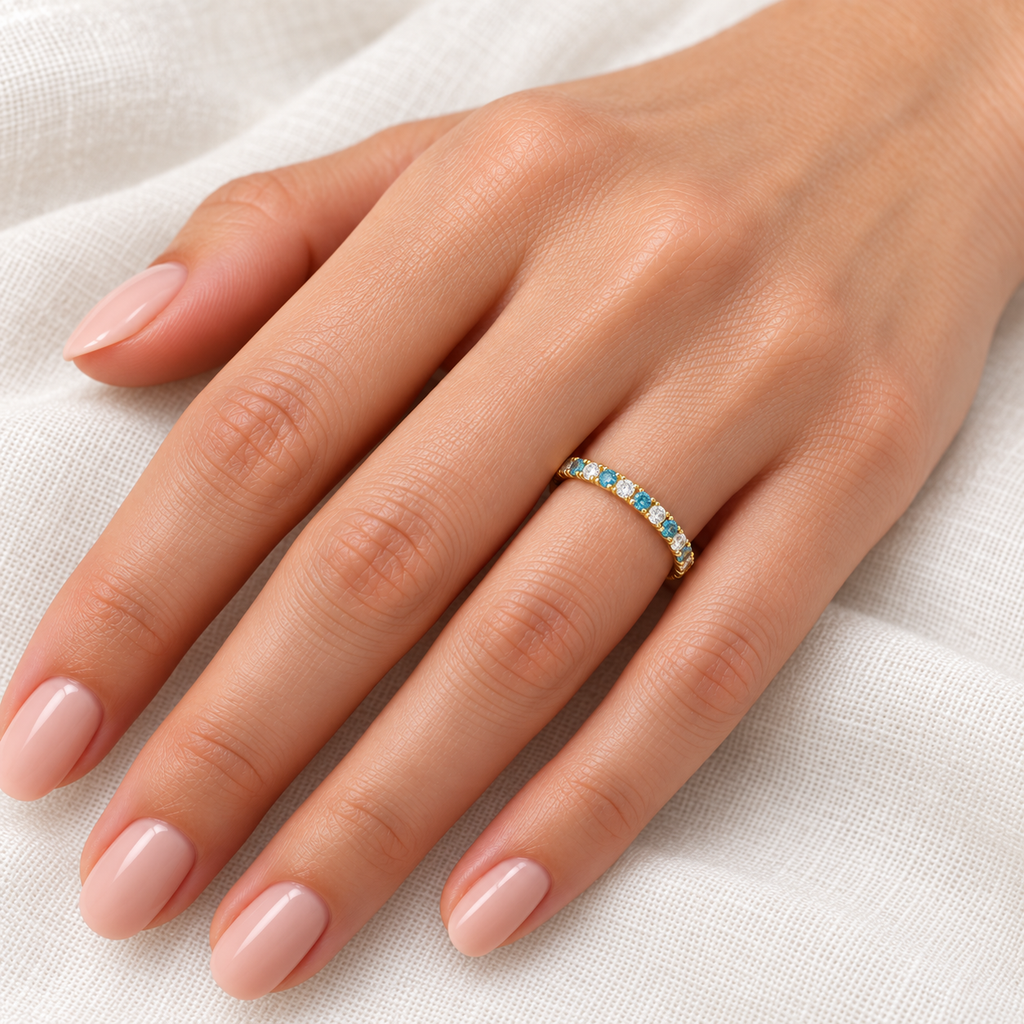 Alternating fancy blue and white diamond 14K yellow gold 2 mm eternity band on left hand, ivory linen closeup